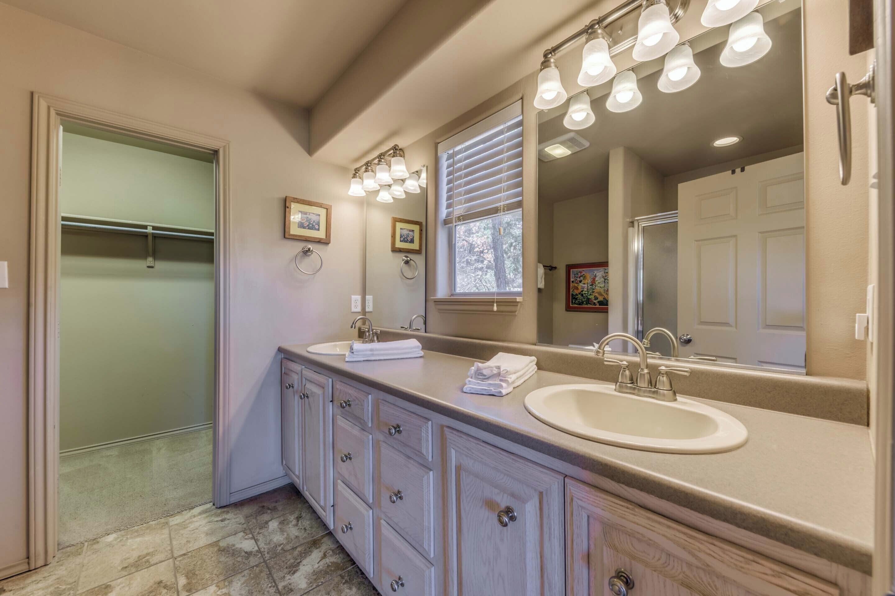 A bathroom with a double sink vanity, a large mirror, and a walk-in closet.
