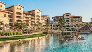 A resort with multiple-story buildings, a swimming pool, and palm trees.