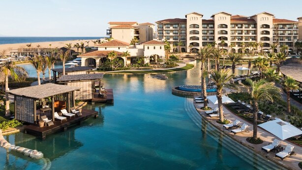 A resort with a central pool, lounge areas, and a beachfront view.