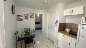 Una cucina compatta con mobili bianchi, un tavolo con sedie, un frigorifero e un forno a microonde.
