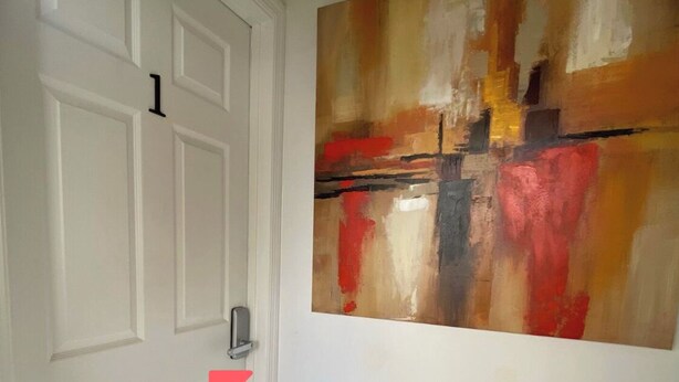 Un corridoio con una porta bianca e un grande quadro astratto appeso al muro.