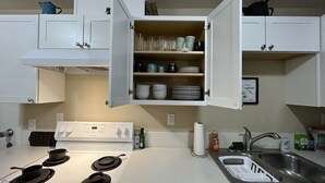 A kitchen with white cabinets, a stove, a sink, and various kitchenware. - Scout- a rustic “cabin” apartment, very fast wifi (Salem)