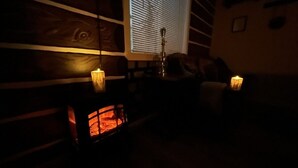 A dimly lit room with a fireplace, a window with blinds, and a wooden wall. - Scout- a rustic “cabin” apartment, very fast wifi (Salem)