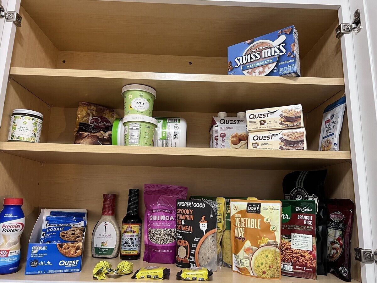 A pantry with various food items including cereal, protein powder, and rice.