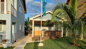 A residential building with a covered porch, a flagpole, and a well-maintained lawn.