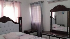 Un dormitorio con una cama, una mesita de noche, un espejo y un equipo de aire acondicionado en la pared.