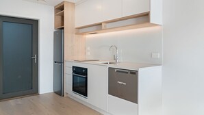 A modern kitchen with built-in appliances, a sink, and wooden shelves.