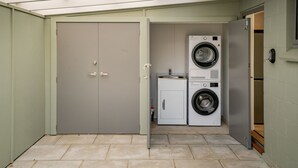 A laundry room with two washing machines, a dryer, and a small cabinet.
