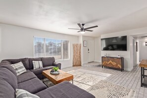 A modern living room with a sofa, coffee table, and a TV mounted on the wall.
