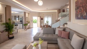 A spacious living area with a grey sofa, a coffee table, and a staircase leading to an upper level. - Cretan Vineyard Hill Villa 2 | Private pool, panoramic view, beautiful vineyard (Άνω Καλεσια)