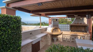 An outdoor kitchen area with a stone countertop, a pizza oven, and a grill. - Cretan Vineyard Hill Villa 2 | Private pool, panoramic view, beautiful vineyard (Άνω Καλεσια)