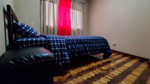 A bedroom with a bed, a pillow, a window with curtains, and a patterned floor. - Apartamento 3 habitaciones y parqueo (Cuenca)