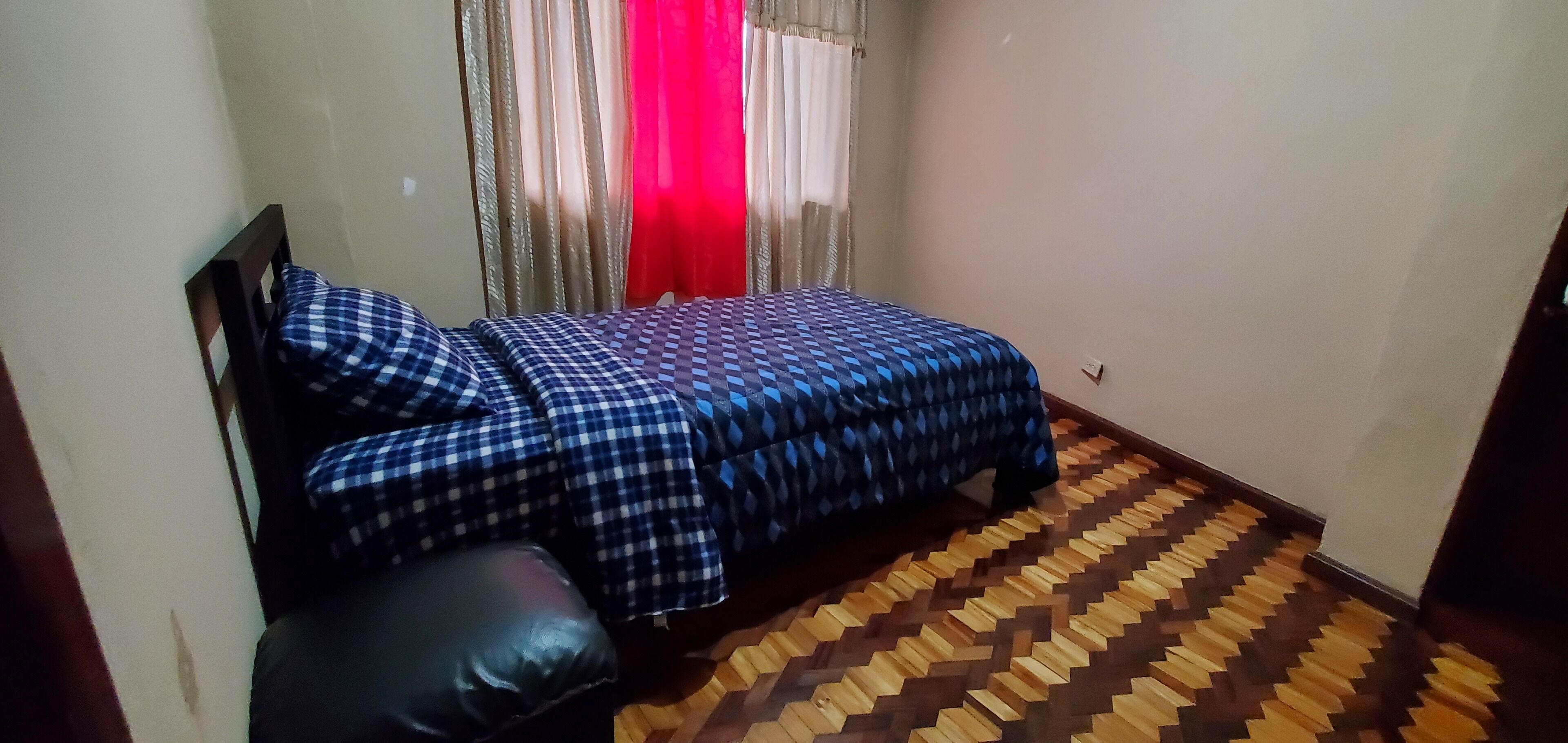 A bedroom with a bed, a pillow, and a patterned floor.