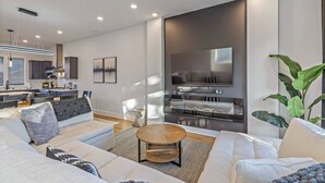 A modern living room with a sofa set, a coffee table, and a TV mounted on a wall.