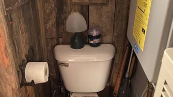 Un baño rústico con un asiento de inodoro de madera, un calendario y un dispensador de papel higiénico.
