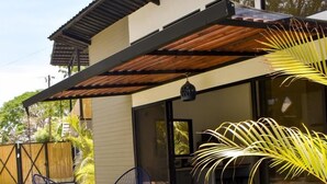 A modern house with a patio, two chairs, and a large window. - Blue Window (Veintisiete de Abril)