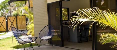 A modern house with a patio, two chairs, and a large window.