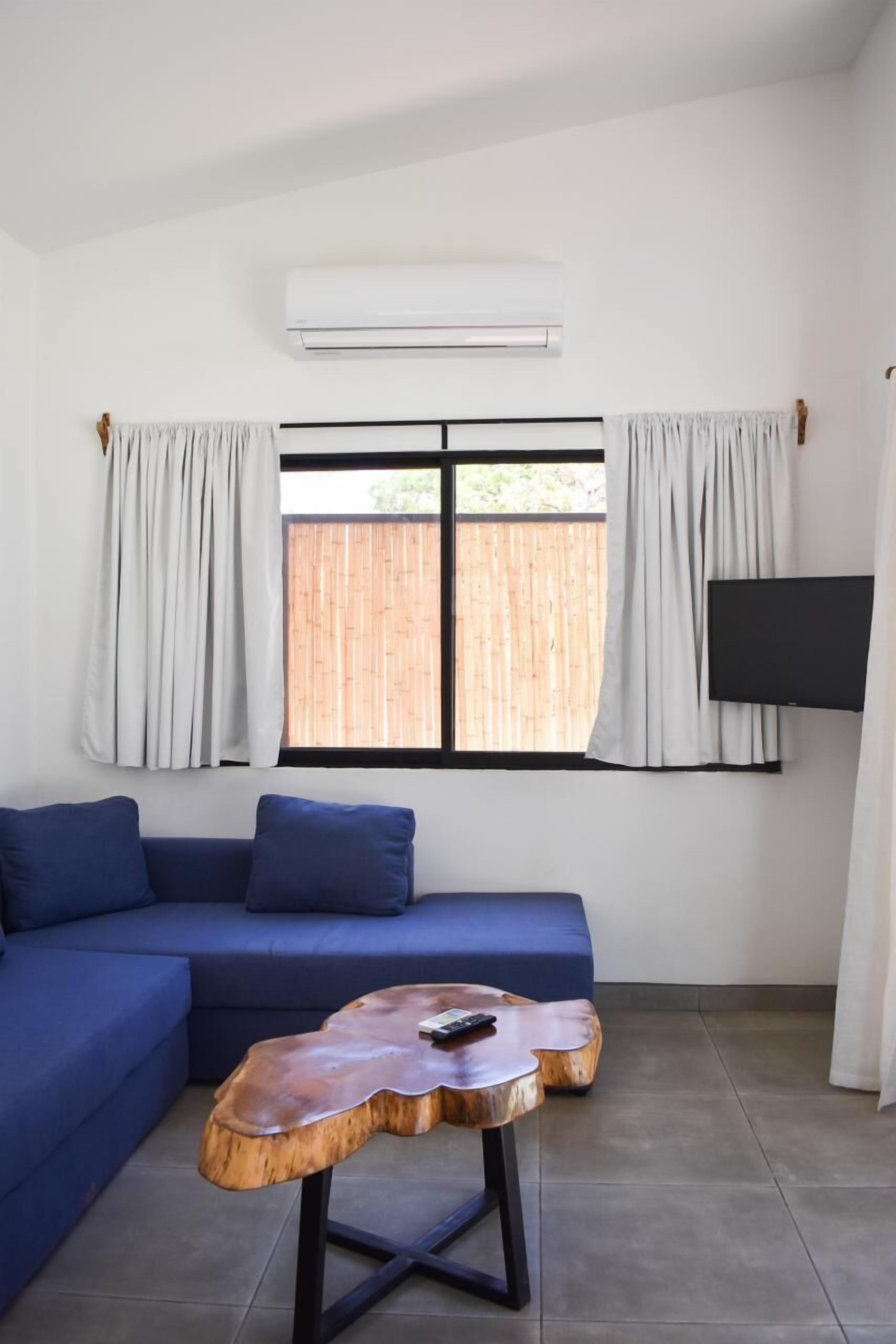 Una sala de estar moderna con un sofá modular, una mesa de centro de madera y un televisor de pantalla plana montado en la pared.