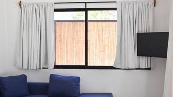 Una sala de estar moderna con un sofá modular, una mesa de centro de madera y un televisor de pantalla plana montado en la pared.