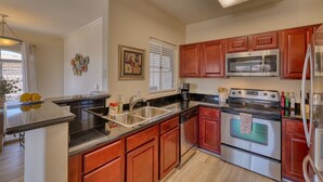 A kitchen with wooden cabinets, stainless steel appliances, a double sink, and a window with blinds. - Paradise Valley area condo with heated pool and gym,  near Mayo Clinic. (Scottsdale)