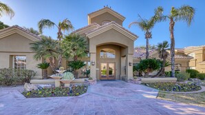 A residential building with a tiled entrance, palm trees, and a variety of plants. - Paradise Valley area condo with heated pool and gym,  near Mayo Clinic. (Scottsdale)