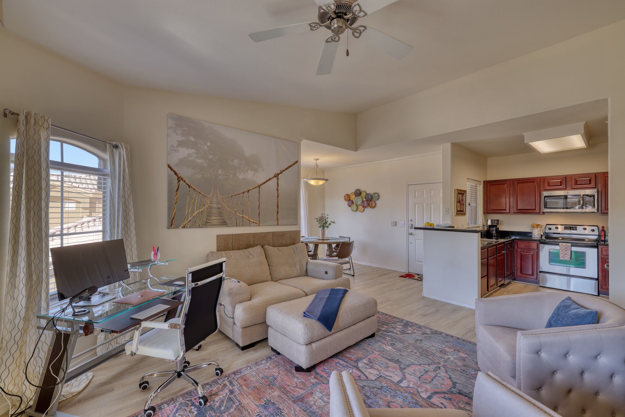 A spacious living area with a glass desk, a sofa, and a dining table.