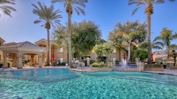 A clear swimming pool with a fountain, surrounded by palm trees and lounge chairs. - Paradise Valley area condo with heated pool and gym,  near Mayo Clinic. (Scottsdale)