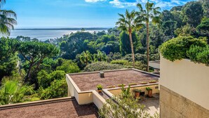 Una terraza en la azotea con vistas al océano, rodeada de vegetación exuberante y palmeras.