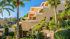 Un edificio de varios pisos con balcones, rodeado de abundante vegetación y palmeras.