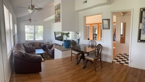 A spacious living room with a wooden floor, a dining table with chairs, a sofa, and a TV. - 35 min to Louisville, 45 to Churchill Downs. Indoor Basketball court. (Fredericksburg)