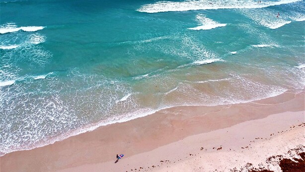 Una playa con agua turquesa cristalina y una orilla arenosa.