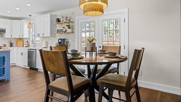 A modern kitchen with white cabinets, a dining table with chairs, and a hanging light fixture. - Quiet and Cozy with Outdoor Space (Duncan)