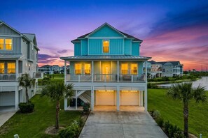 A two-story residential building with a balcony, a garage, and a well-maintained lawn.