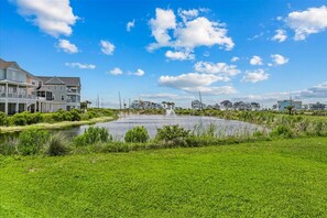 A residential area with houses, a pond, and a clear sky.