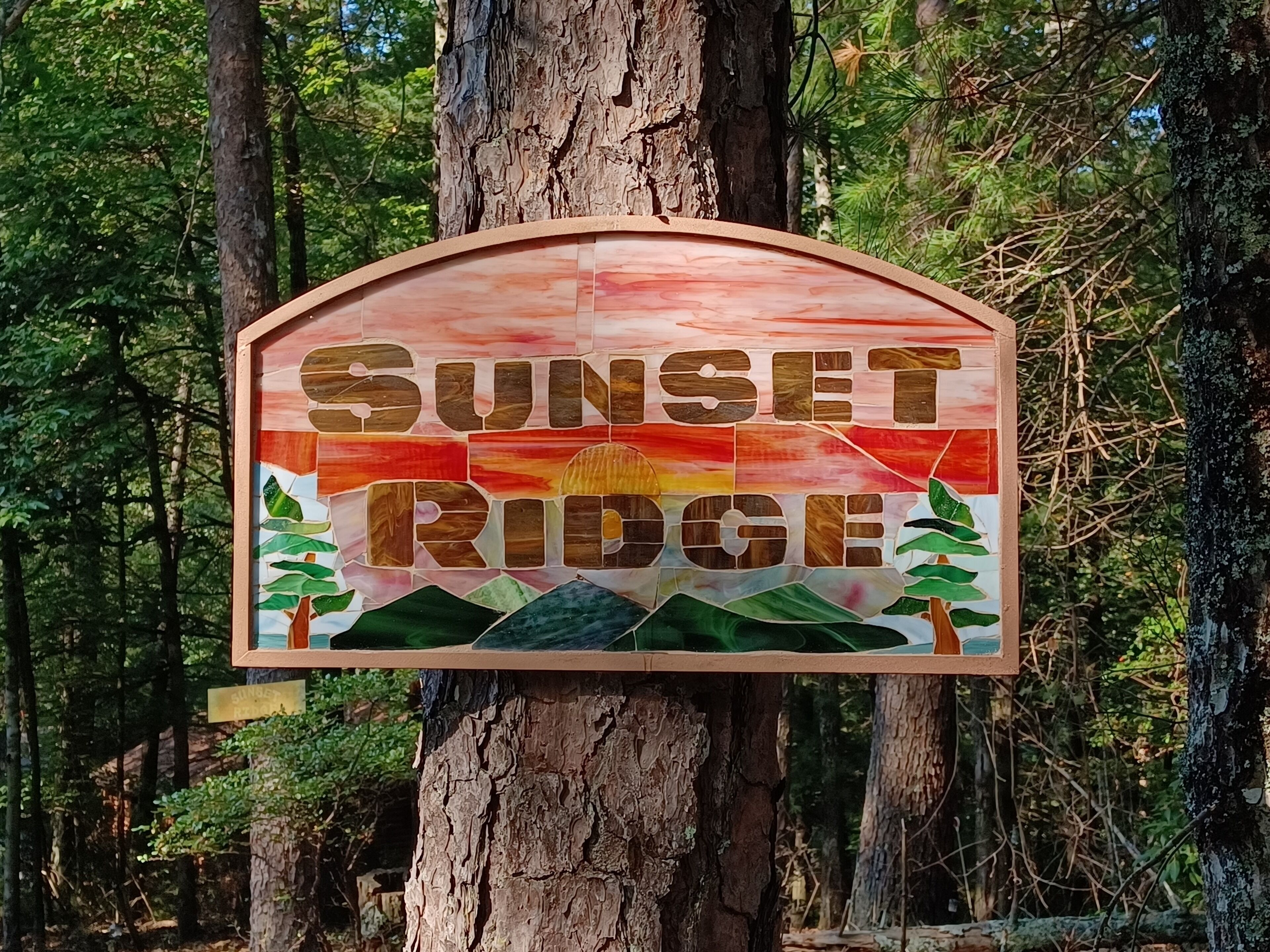 A wooden sign with the words "Sunset Ridge" and a landscape design.