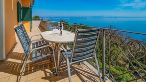 A balcony with a table and chairs, overlooking a scenic view of the sea. - Beautiful apartment in Moscenicka Draga (Moscenicka Draga)