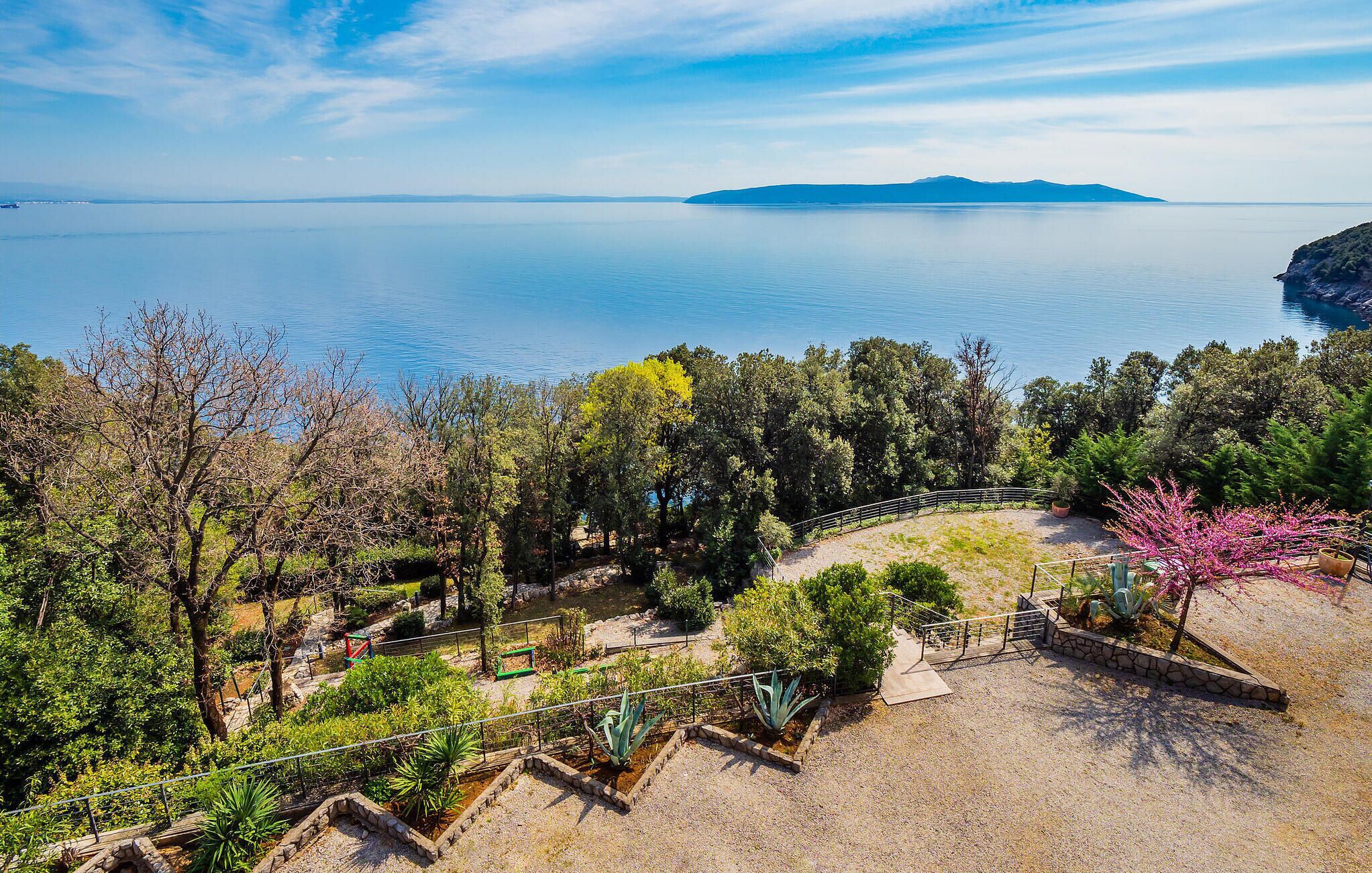 A coastal landscape with a clear view of the sea and distant mountains.