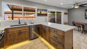 Una cucina moderna con mobili in legno, lavastoviglie in acciaio inox e piano di lavoro bianco.
