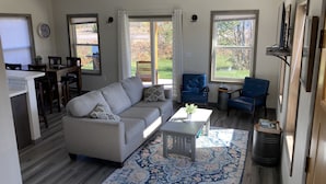 Un salon moderne avec un canapé gris, des fauteuils bleus, une table basse et un tapis à motifs.