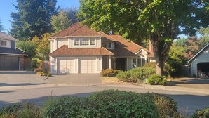 A two-story house with a garage, surrounded by well-maintained lawns and trees. - House in Bellevue (Bellevue)