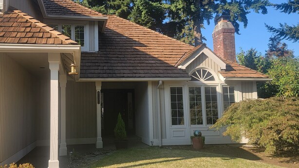 A two-story house with a brown shingled roof, a brick chimney, and a covered front porch. - House in Bellevue (Bellevue)