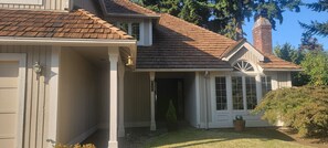 A two-story house with a brown shingled roof, a brick chimney, and a covered front porch. - House in Bellevue (Bellevue)
