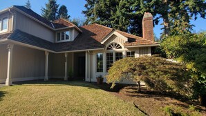 A two-story house with a garage, a covered porch, and a brick chimney. - House in Bellevue (Bellevue)