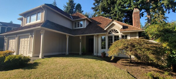 A two-story house with a garage, a covered porch, and a brick chimney.