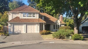 A two-story house with a garage, a covered porch, and a brick chimney. - House in Bellevue (Bellevue)