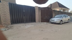A gated driveway with a parked car and a house in the background. - Have a Quality time with your Family in this  3bed apartment on the ground floor (Lagos)