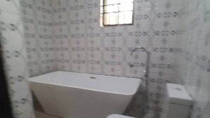 A bathroom with a bathtub, toilet, and a small window. - Have a Quality time with your Family in this  3bed apartment on the ground floor (Lagos)