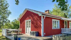 Una casa di legno rossa con un portico, un piccolo patio e una finestra.