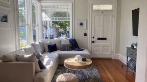 Una sala de estar con un sofá modular, una mesa de centro redonda, una alfombra y una puerta con un ventanal pequeño.