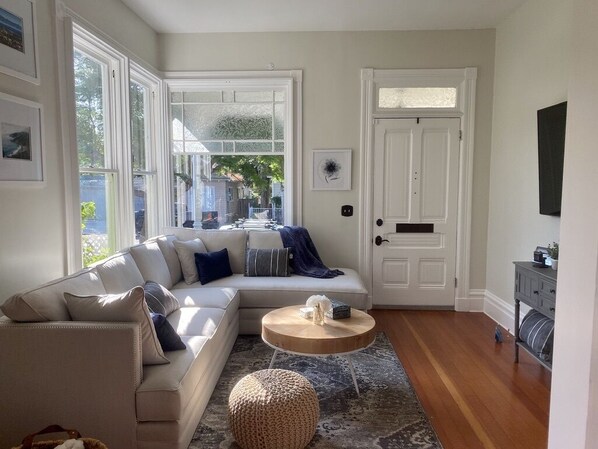 A living room with a sectional sofa, a round coffee table, a rug, and a door with a small window.